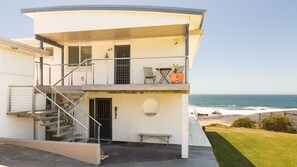 Un edificio de dos pisos con un balcón, una escalera y un banco.