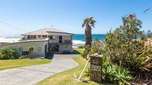 A coastal property with a two-story house, a paved driveway, and a stone mailbox.