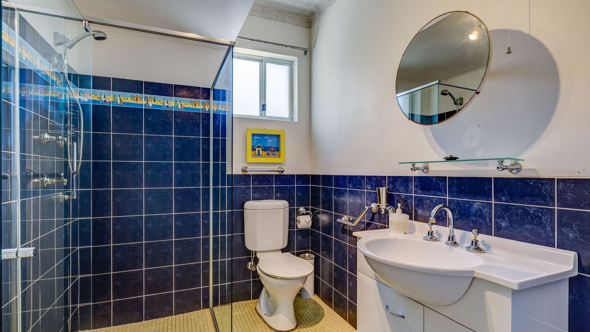 Ein Badezimmer mit Duschkabine, Toilette, Waschbecken und Spiegel.