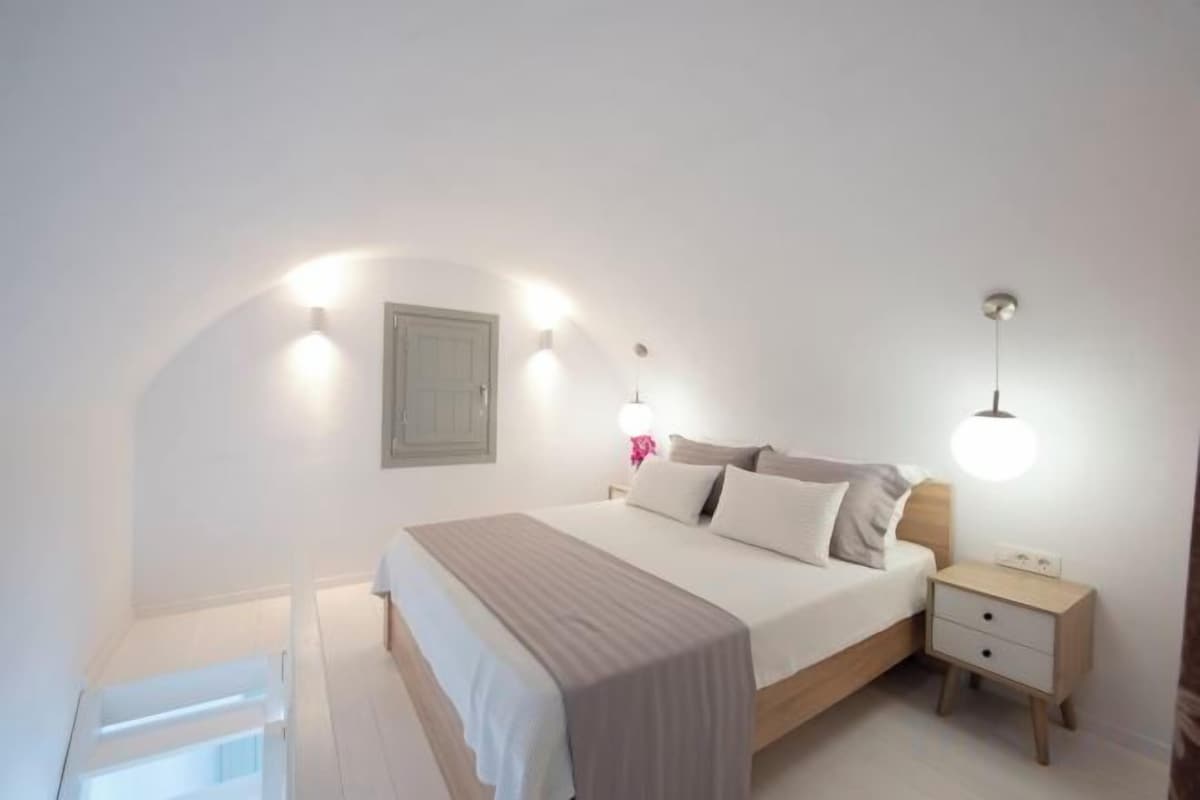 Une chambre à coucher avec un lit, une table de chevet et des lampes fixées au mur.