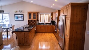 Una cocina con armarios de madera, un refrigerador de acero inoxidable y un comedor con mesa y sillas.