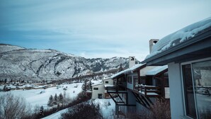 Paisaje nevado de montañas con una zona residencial que cuenta con casas modernas, balcones y ventanas amplias.