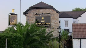 Un edificio de piedra con un letrero que dice "The Badger Inn" y un cartel de "St. Austell Ales" al fondo.