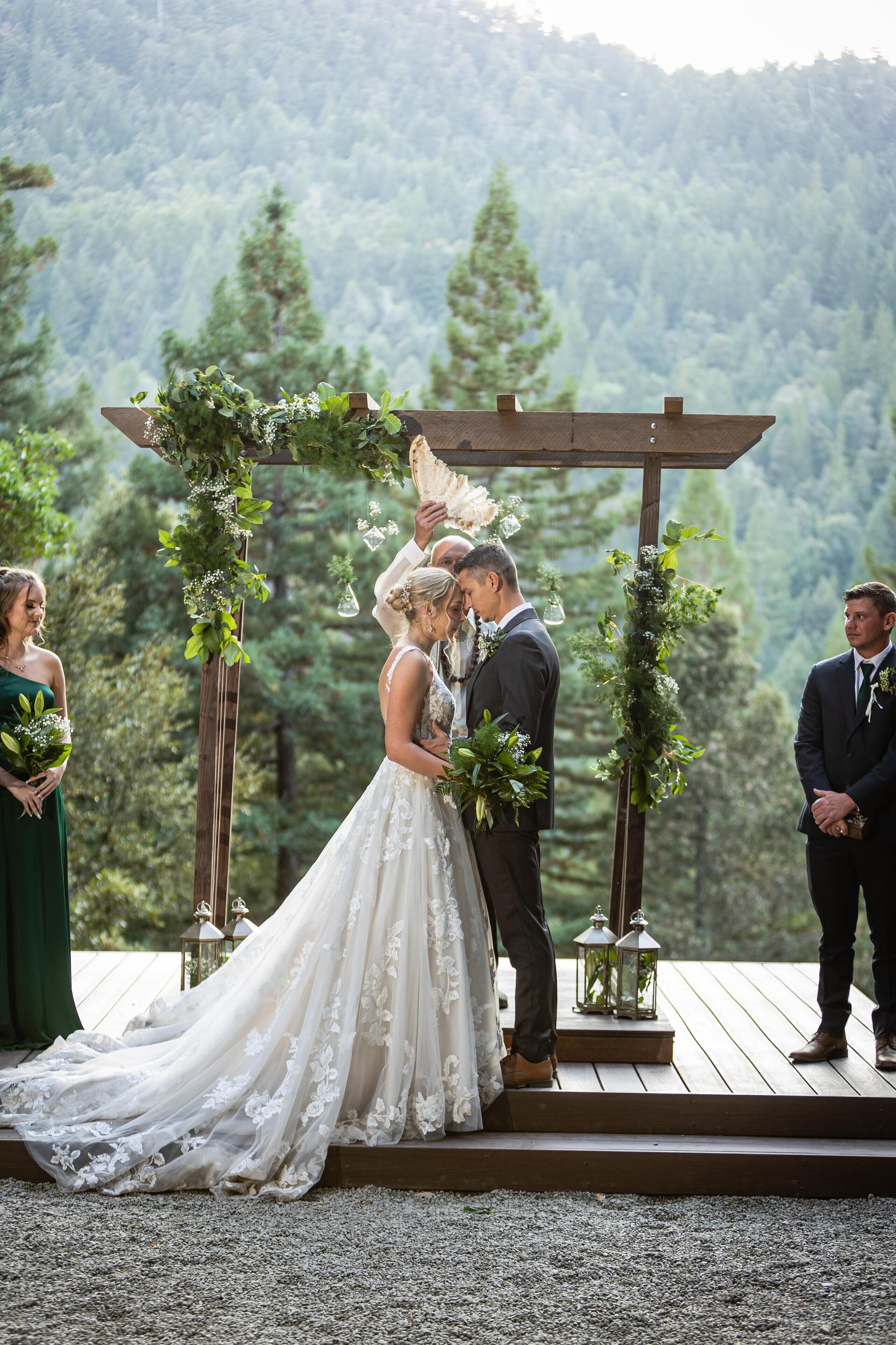 Una ceremonia de boda al aire libre con una plataforma de madera y follaje.