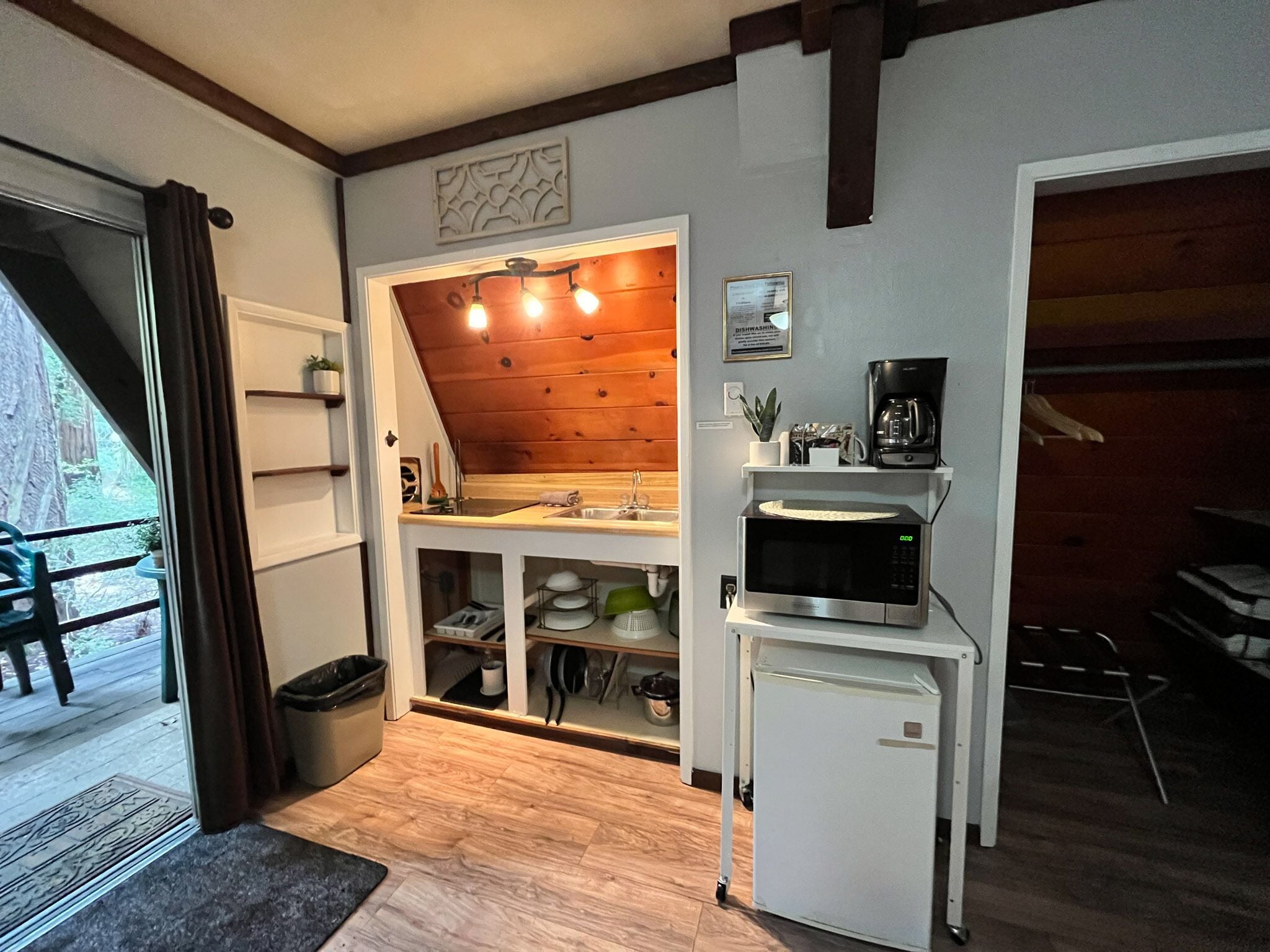 Eine kleine Küche mit Holzbalkendecke, Spüle, Mikrowelle und Kühlschrank.