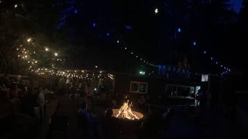 Un área de comedor al aire libre con luces colgantes y una chimenea.