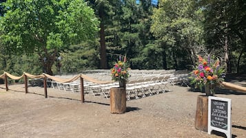 An outdoor wedding venue with rows of white chairs, a wooden fence, and a welcome sign.