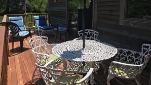 A wooden deck with outdoor furniture, including a round table with chairs and lounge chairs. -  Charming 2 bedroom rental Pond Village area available  June 8-17 (north truro)