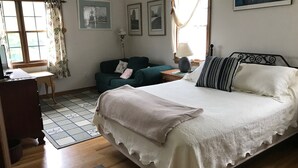 A bedroom with a bed, a desk, a sofa, and a window with curtains. -  Charming 2 bedroom rental Pond Village area available  June 8-17 (north truro)