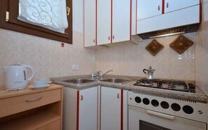 Een kleine keuken met een gasfornuis, een spoelbak en een aanrecht.