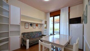 Una cucina compatta con tavolo da pranzo, divano e frigorifero.