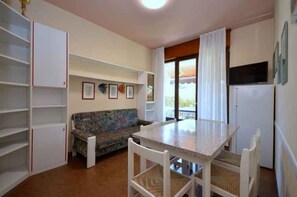 Une cuisine compacte comprenant une table à manger, un canapé et un réfrigérateur.
