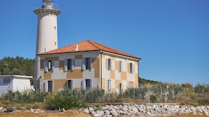 A lighthouse with a red-tiled roof and a two-story building with checkered walls.