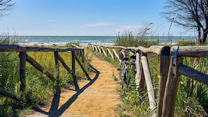 A wooden pathway leading to a beach with a bicycle parked by the side.
