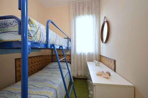 Une chambre avec des lits superposés, un bureau et une fenêtre avec des rideaux.