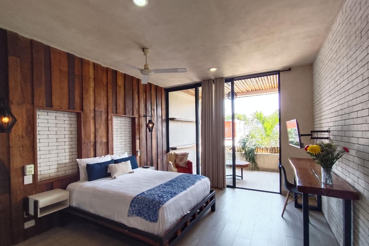 Quarto moderno com uma cama grande, uma escrivaninha e vista para o exterior.