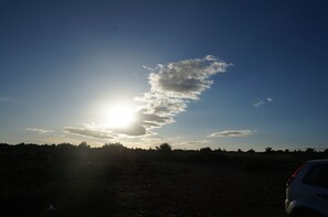 Un coche aparcado en un campo con cielo despejado y sol brillante.