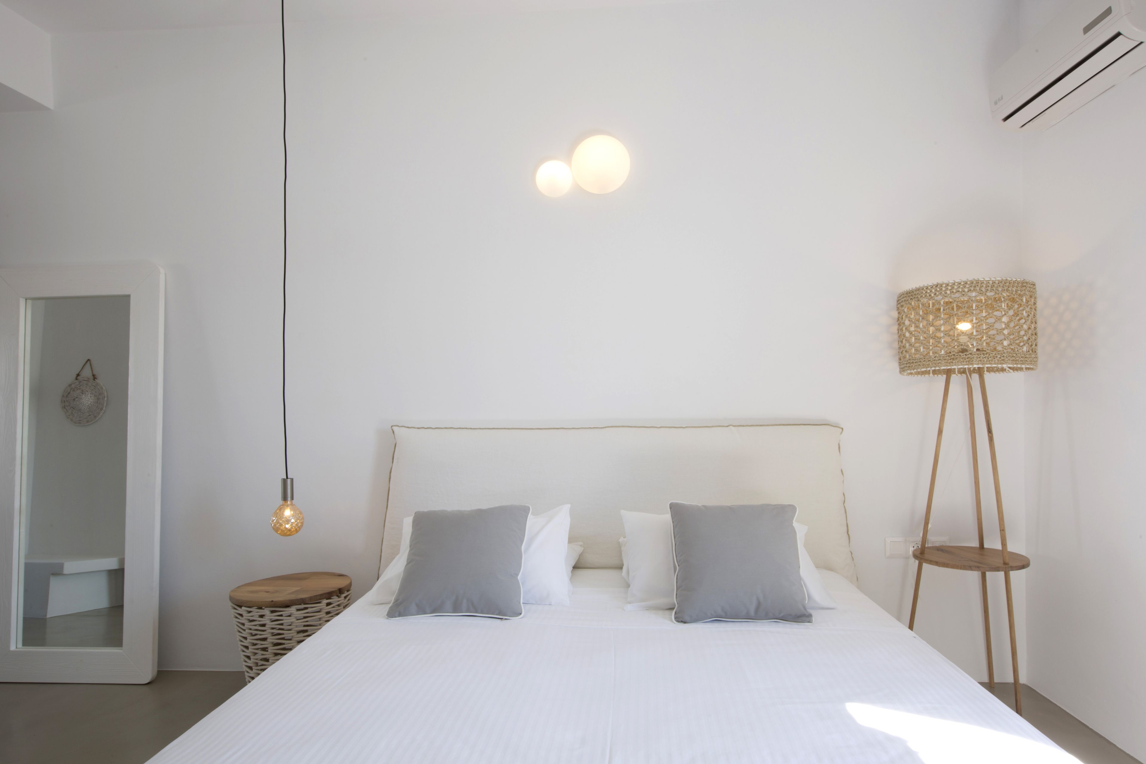 Quarto com cama grande, mesas de cabeceira, abajur e espelho.