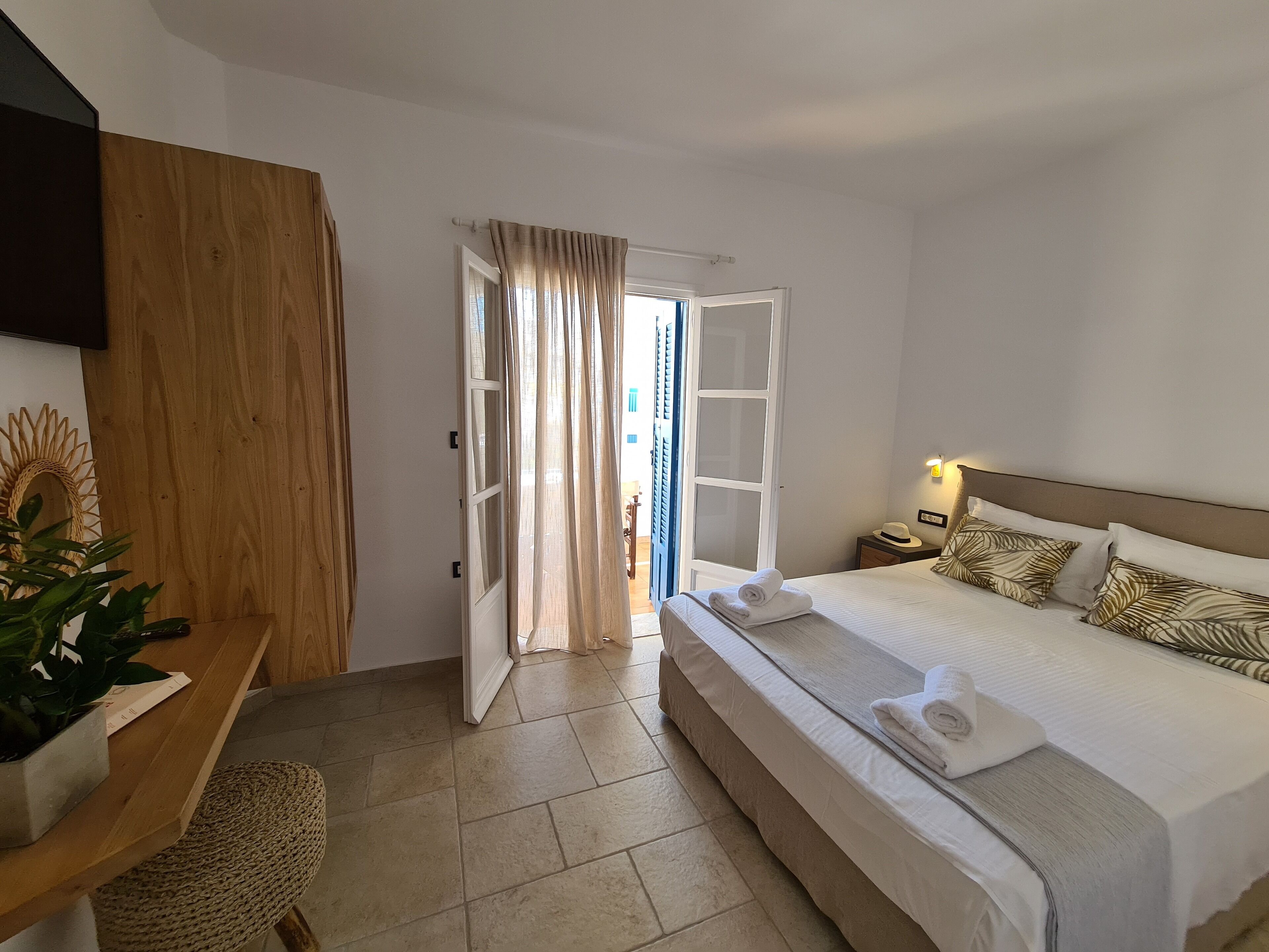 Una habitación de hotel con una cama, mesita de noche y vistas al exterior.