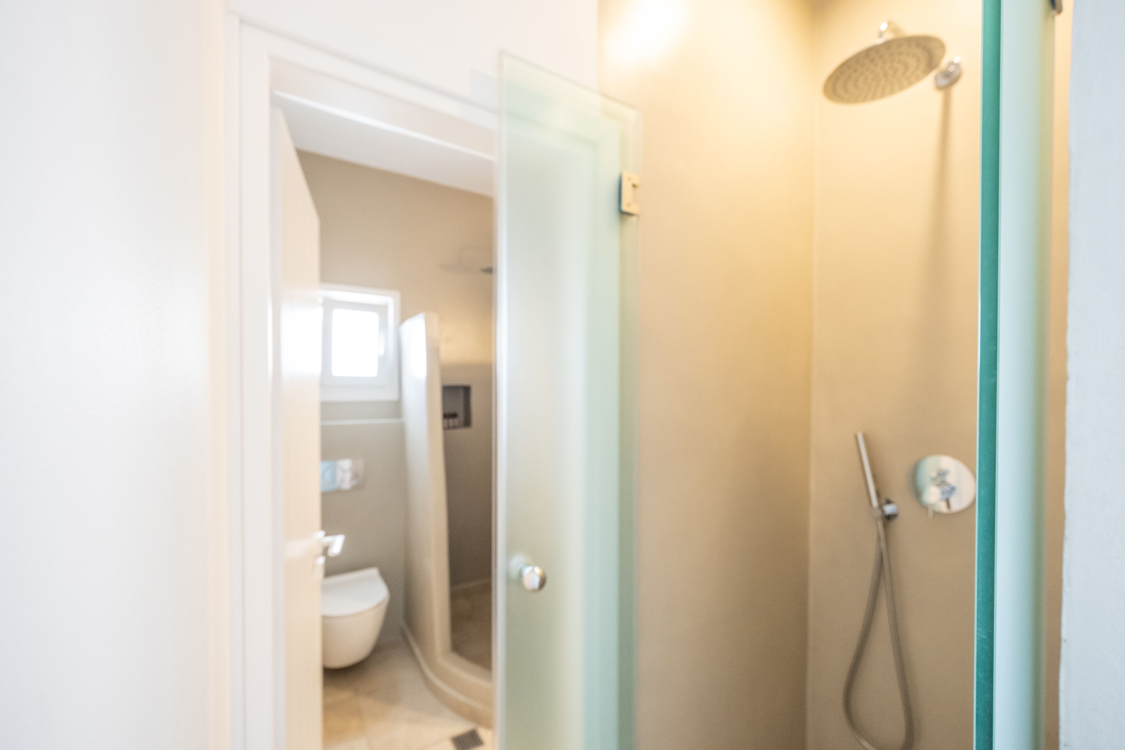 A bathroom with a glass shower door, a toilet, and a showerhead.