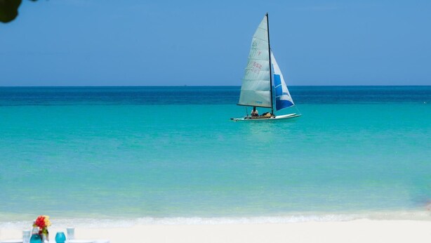 A sailboat on turquoise waters with a clear sky. - Secret Cabins at Firefly Beach (Negril)