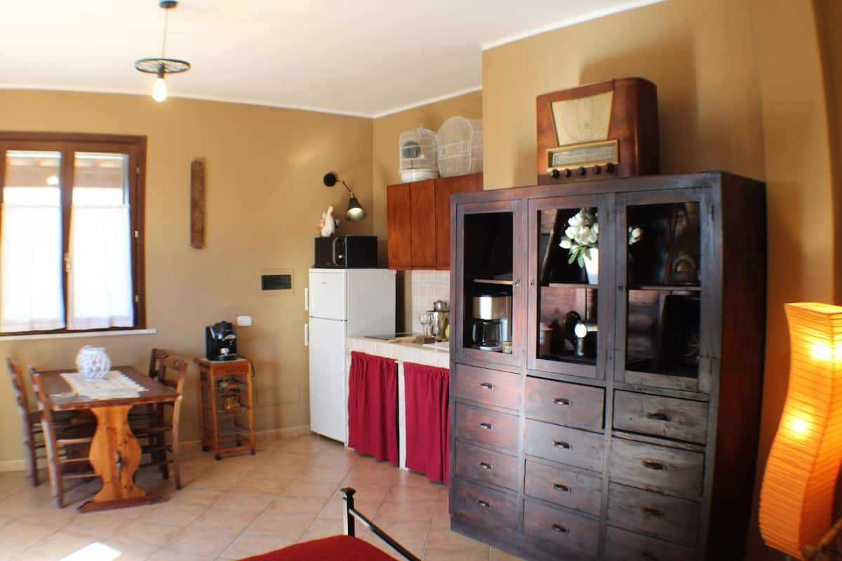 Une cuisine avec des meubles de rangement en bois, une table à manger, des chaises, un réfrigérateur et une machine à café.