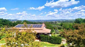 Een huis met zonnepanelen op het dak, omringd door weelderige begroeiing en een prachtig uitzicht op heuvels.