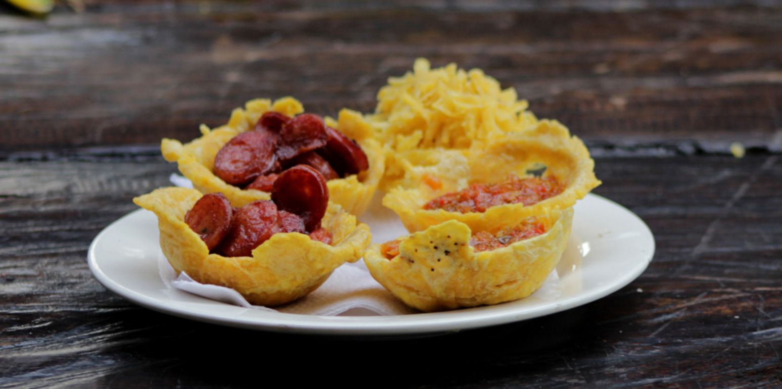 A plate with two food items, one containing a red meat and the other a yellow mixture.