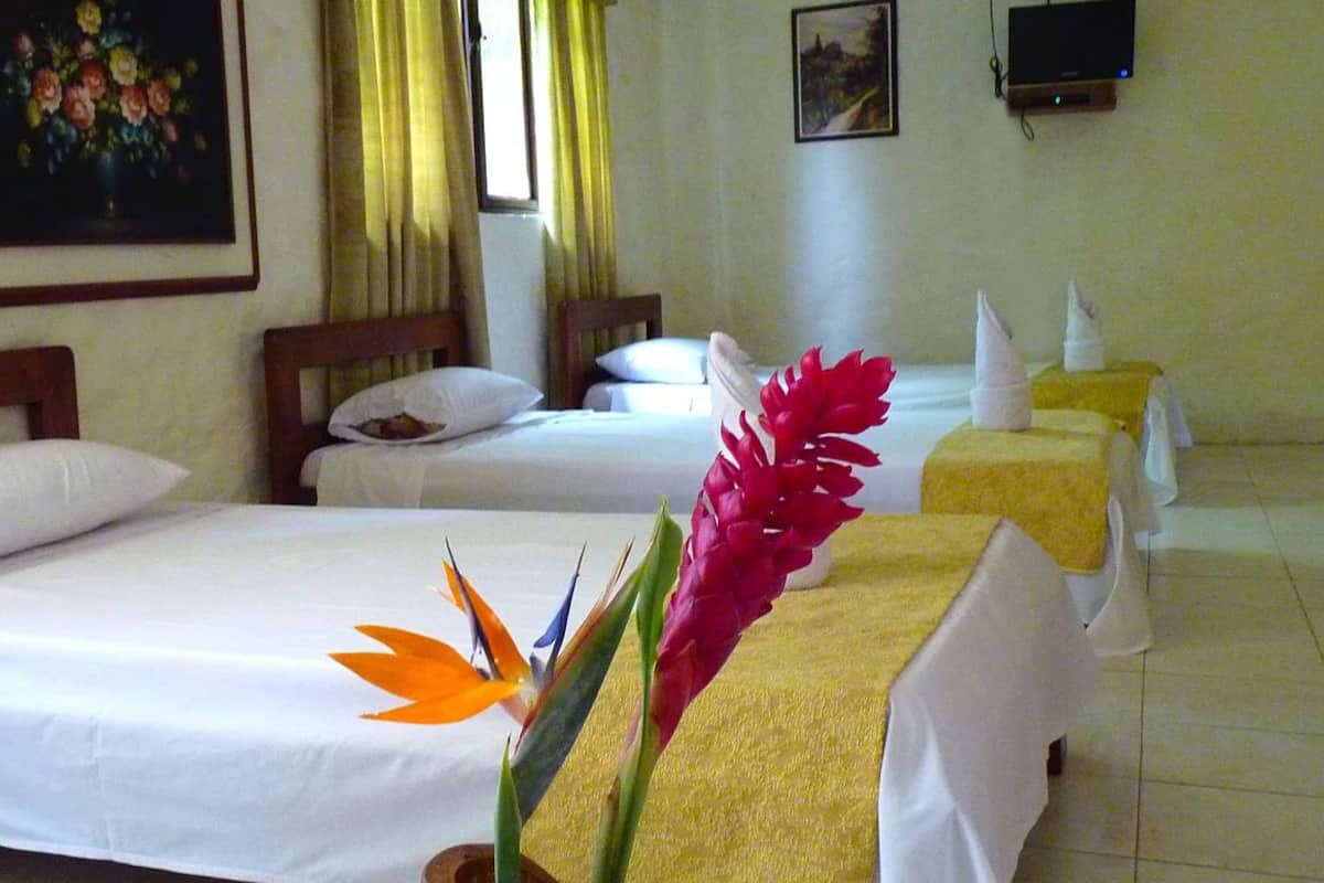 A hotel room with two single beds, a TV, and a painting on the wall.