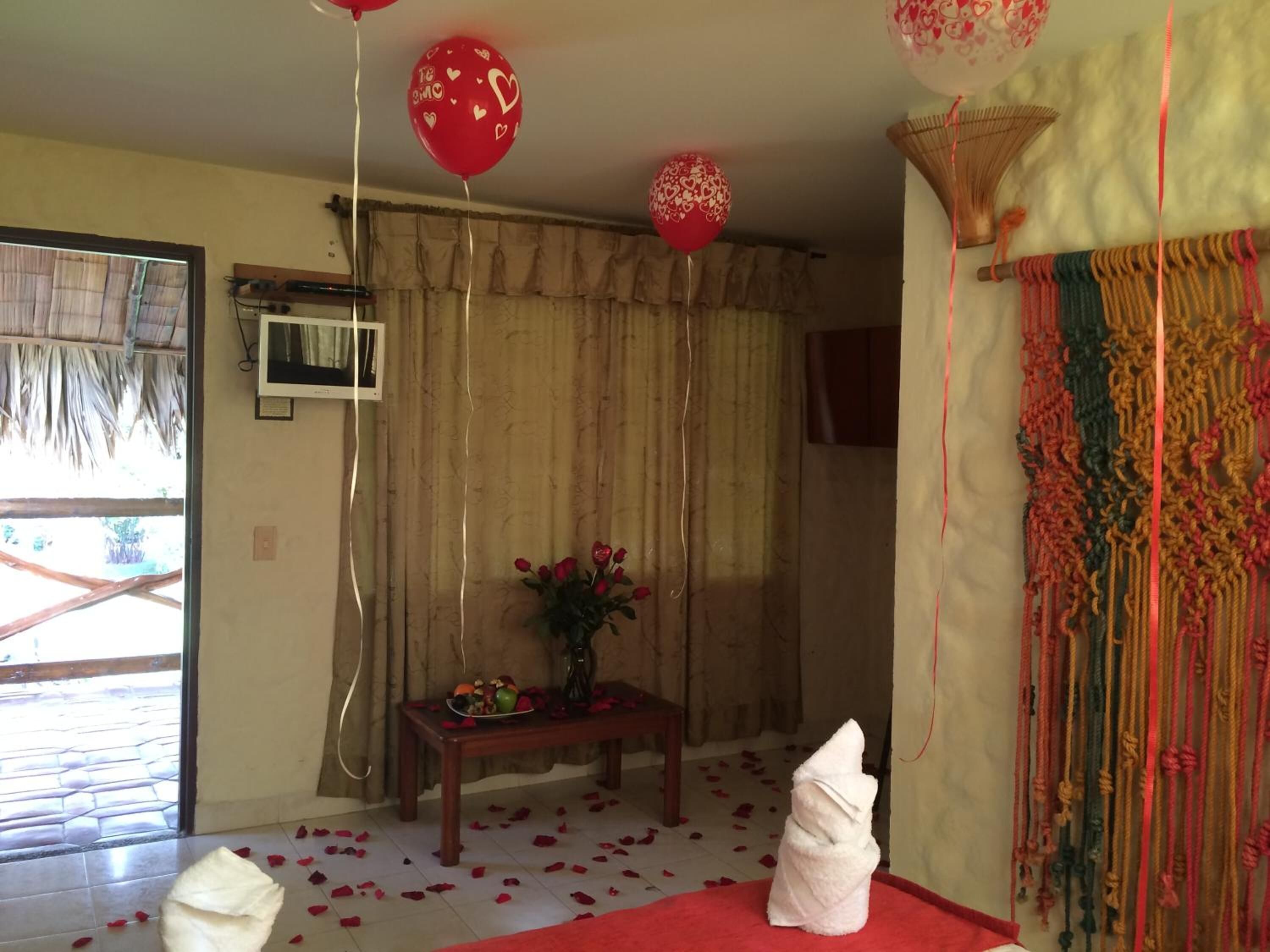 Una habitación con alfombra roja, un ramo de flores sobre una mesa y un tapiz decorativo en la pared.