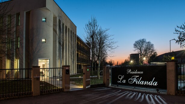 Un immeuble moderne doté d’une entrée sécurisée par un portail, sur laquelle on peut lire l’inscription « Résidence La Filanda ».