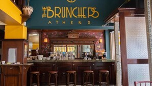A bar area with a counter, stools, and a sign that reads "The Brunchers Athens". - St. Bjur Suites (Athens)