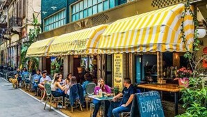 A restaurant with outdoor seating, a chalkboard menu, and a blue awning. - St. Bjur Suites (Athens)