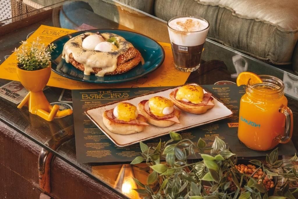 Ein Frühstückstisch mit Eggs Benedict, einer Kaffeetasse und einem Orangensaftkrug.
