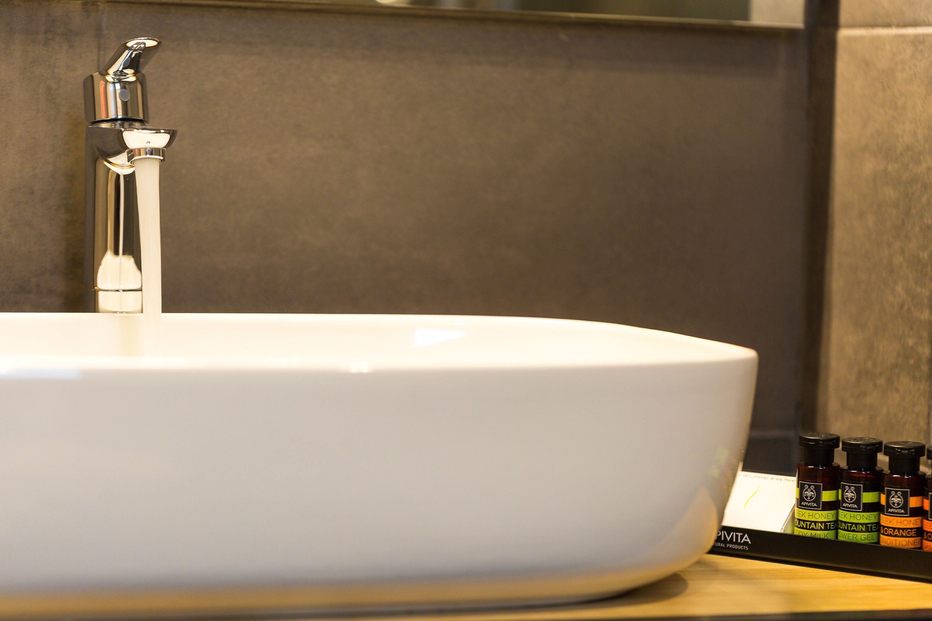 A white sink with a chrome faucet and a bottle of orange essential oil on the counter.