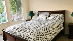 Une chambre à coucher avec un lit, deux lampes de chevet, une fenêtre et une vue sur la verdure.