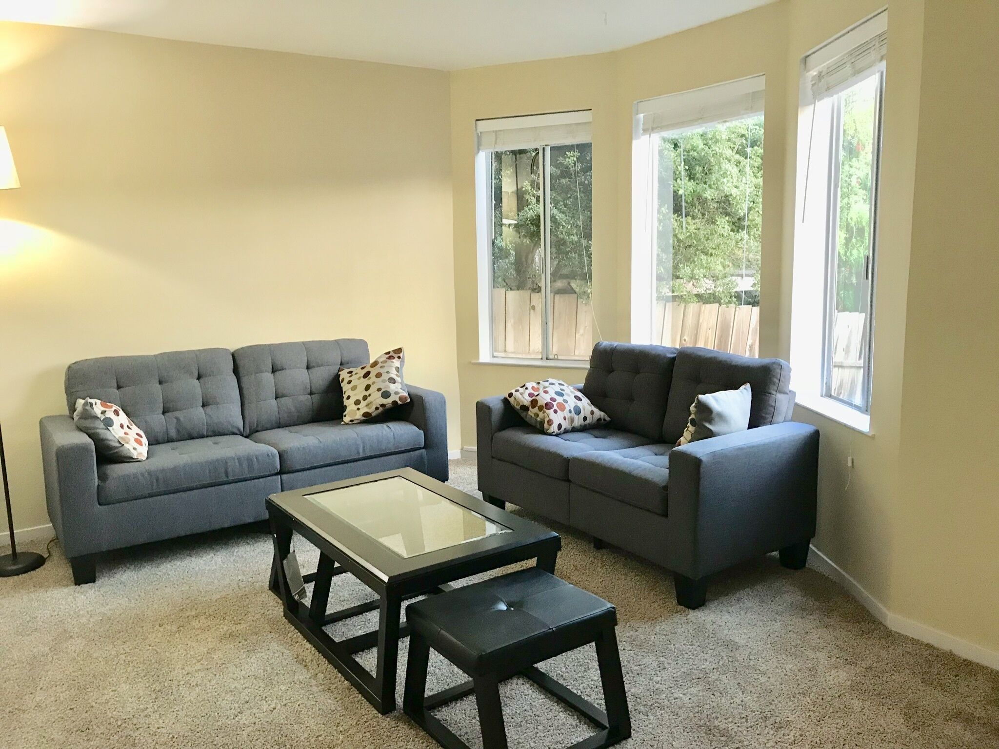 A living room with two grey sofas, a glass-top coffee table, and a black side table.