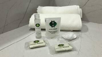 Toiletries including a shampoo bottle, conditioner, and soap bars on a marble countertop in a bathroom.