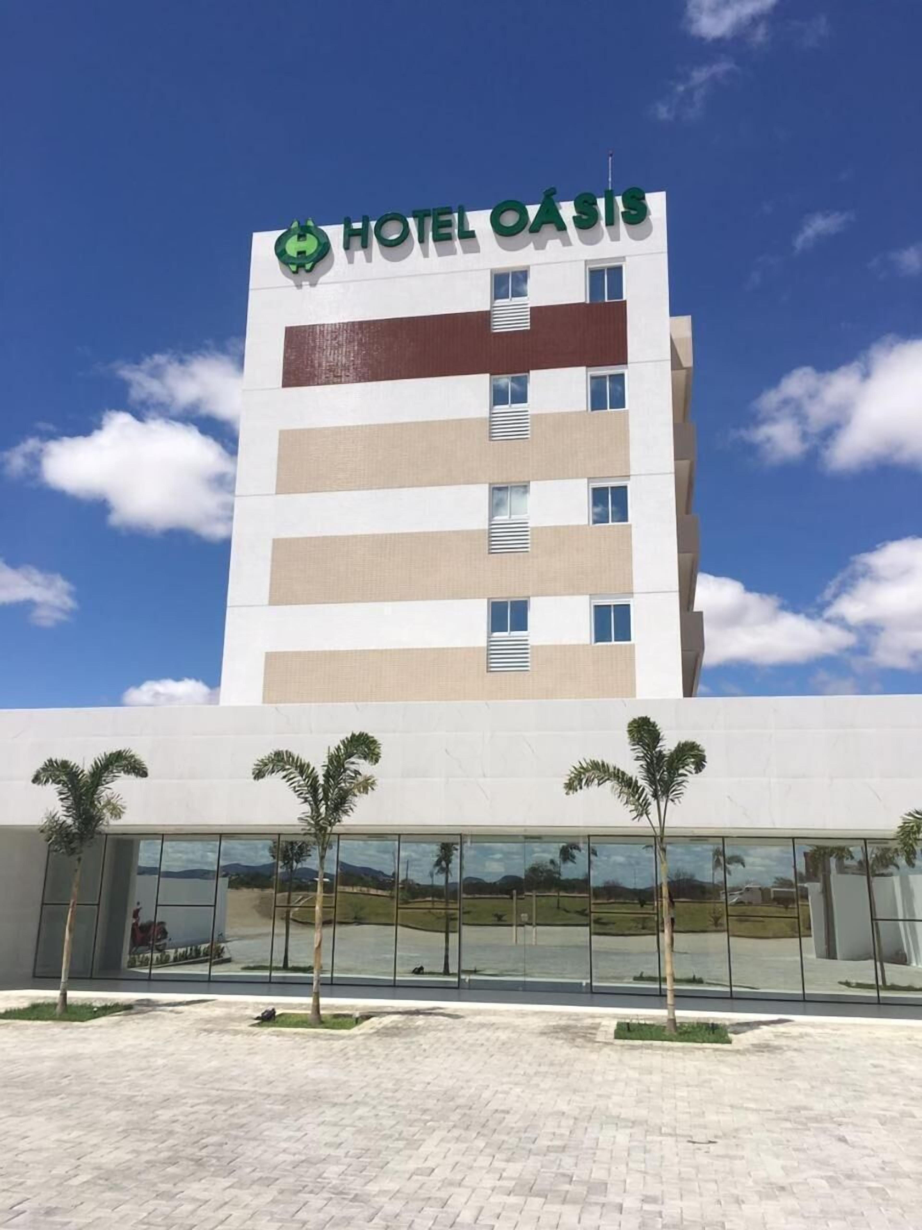 A modern hotel building with a clear sky and palm trees in front.