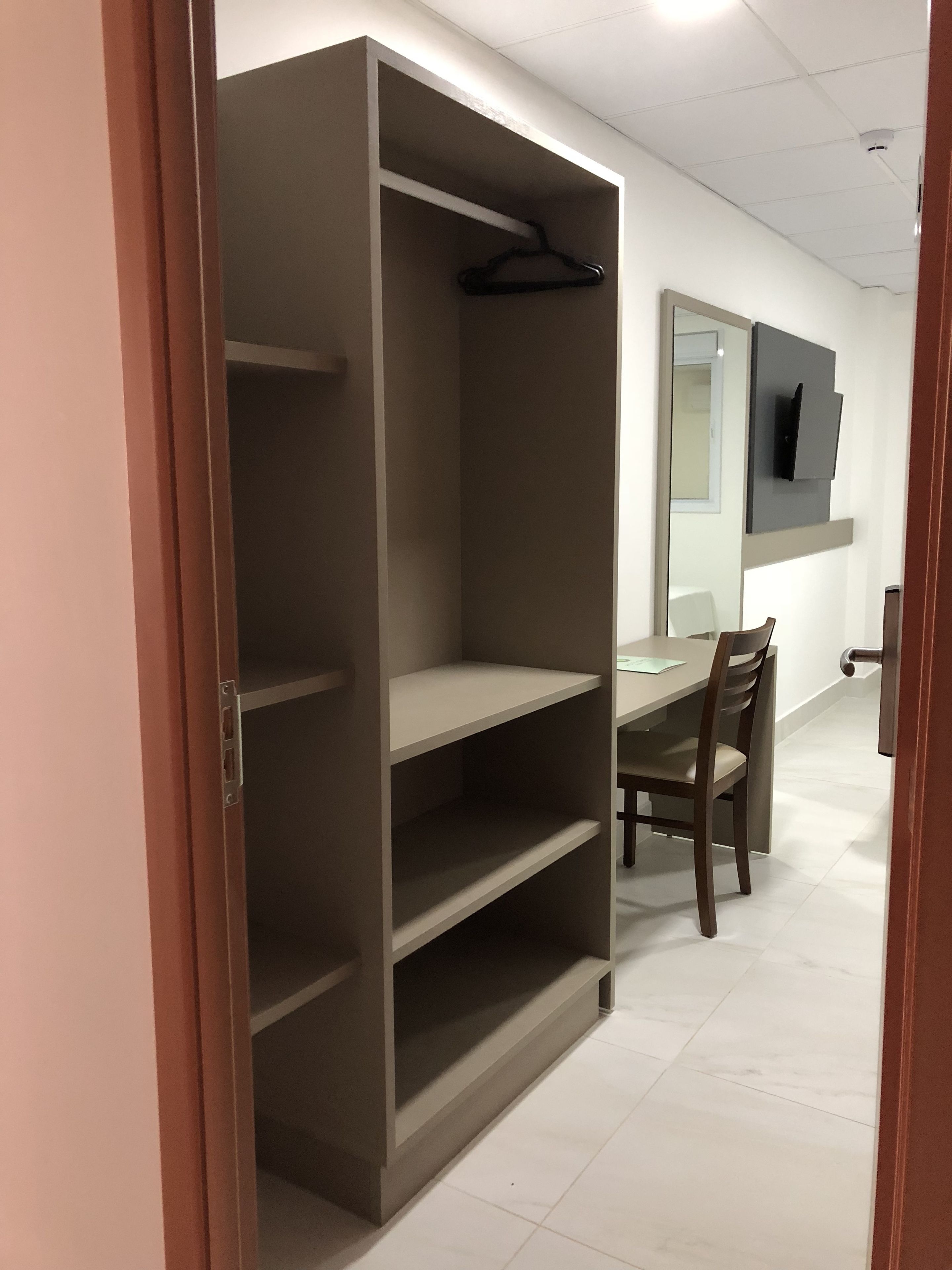 A room with a wardrobe, a table, and a chair.
