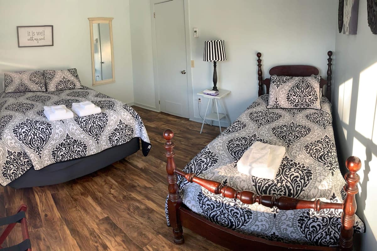 A bedroom with two beds, a mirror, a bedside table, and a chair.
