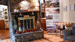 A cozy room with a stone fireplace, wooden furniture, and a table with chairs.