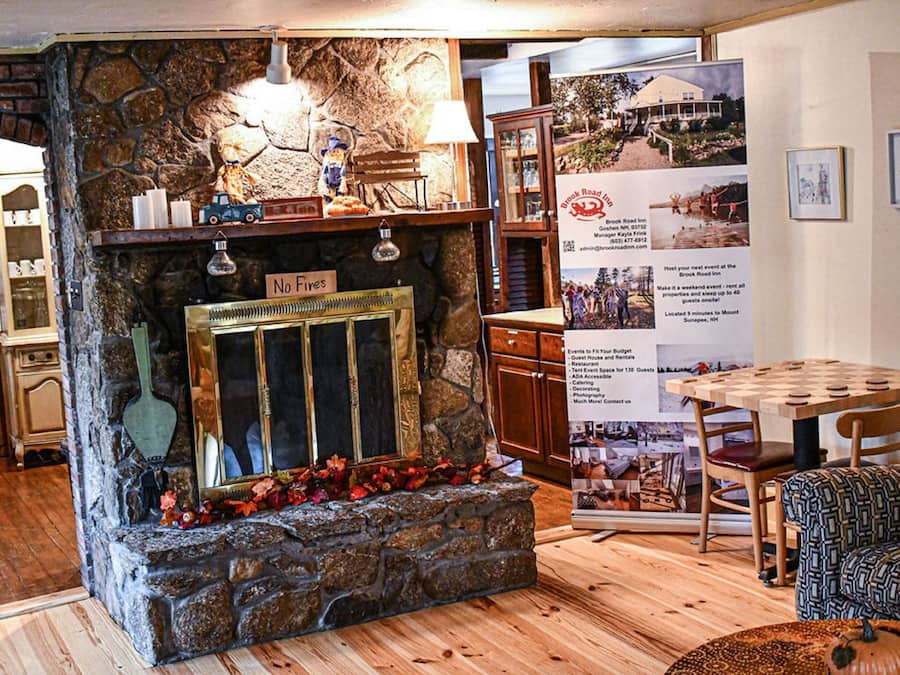 Um quarto aconchegante com lareira de pedra, móveis de madeira e uma mesa com cadeiras.