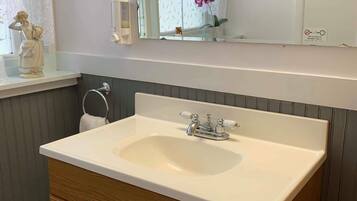 A bathroom with a white sink, wooden vanity, and a mirror above.