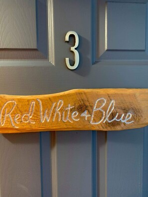 A door with a number '3' and a wooden sign with 'Red White Blue' written on it.