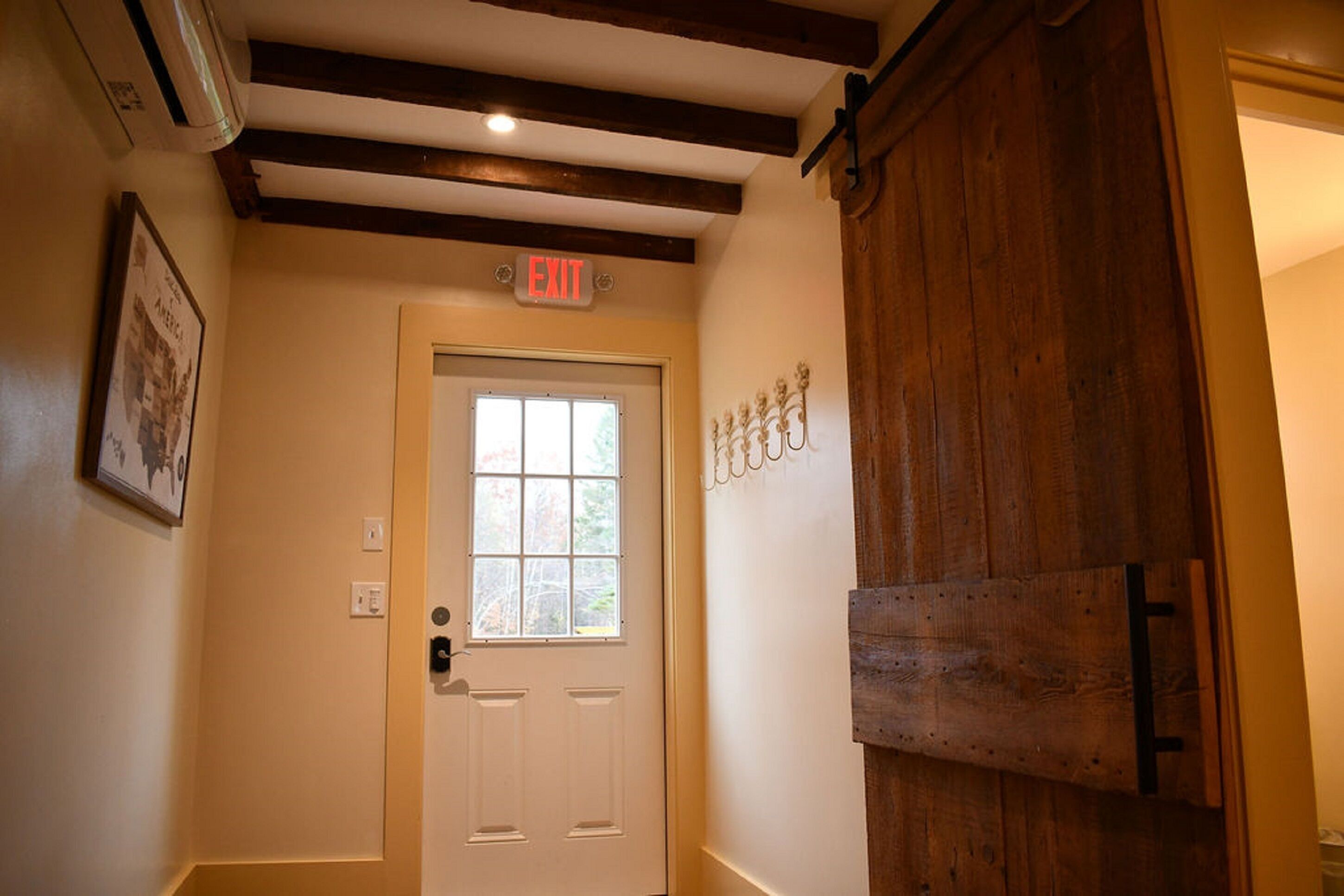 A hallway with a white door, an exit sign, and a wooden door frame.