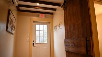 A hallway with a white door, an exit sign, and a wooden door frame.