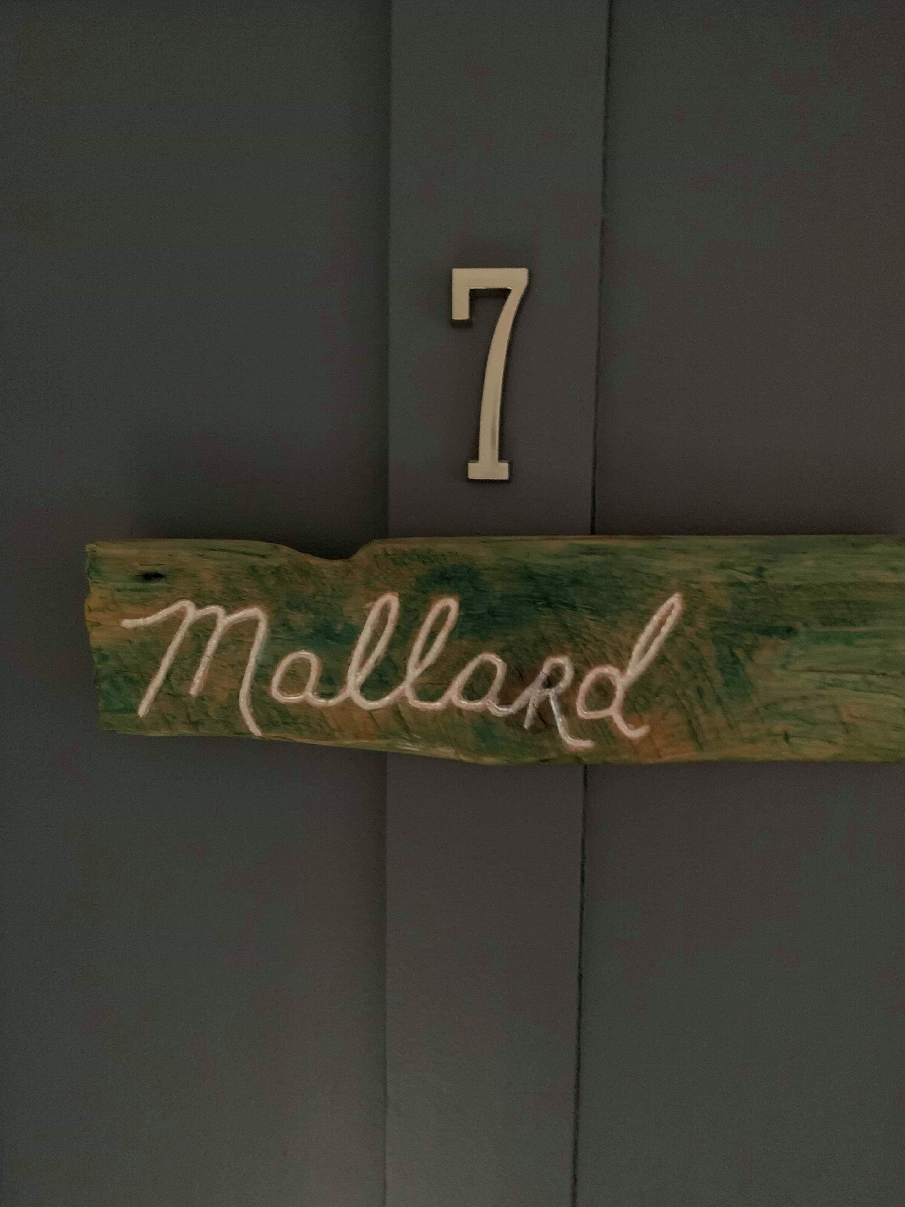 A wooden nameplate with the number 7 and the name 'Mallard' on a dark wall.