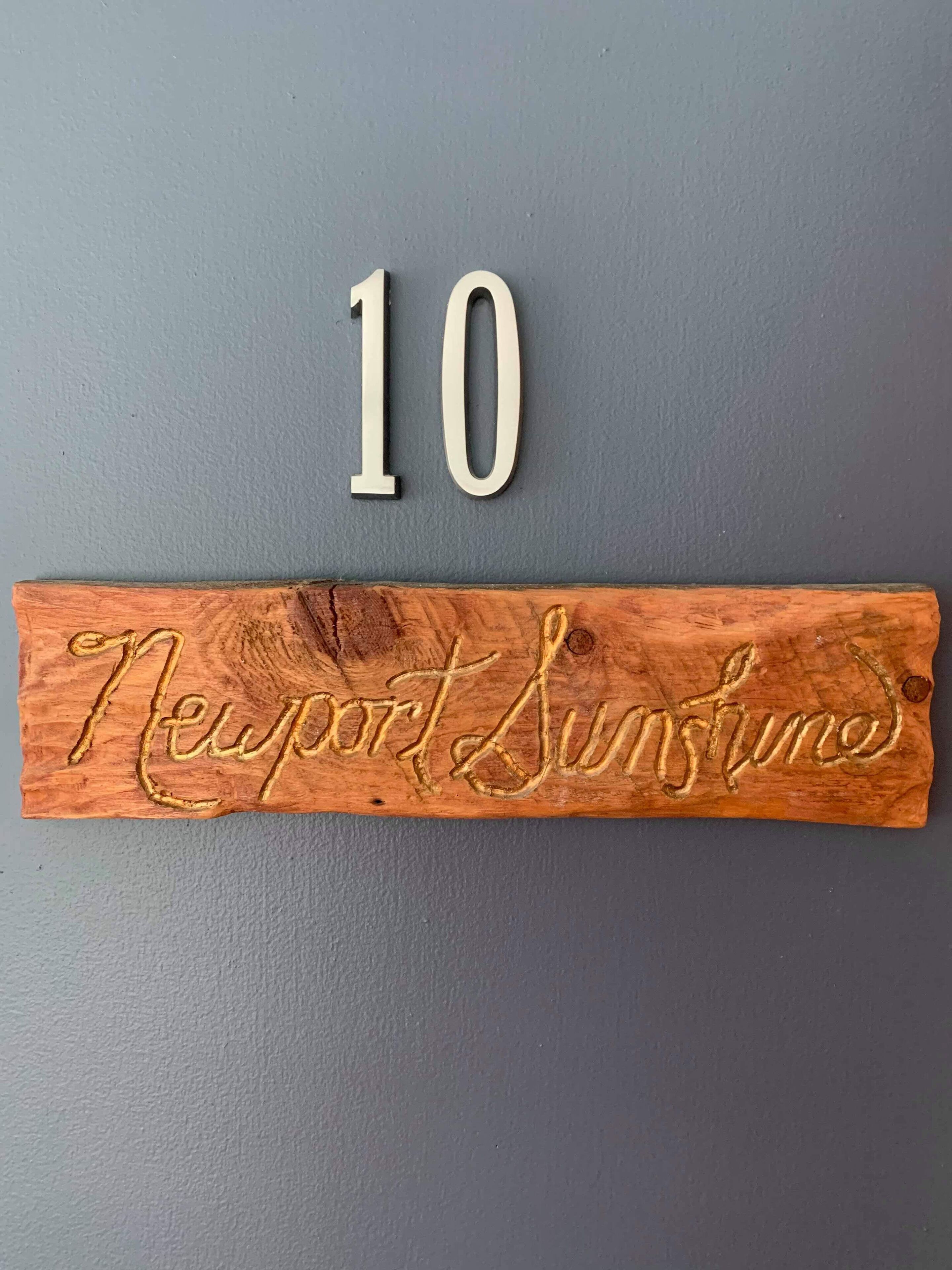 A wooden sign with the number 10 and the words "Newport Sunshine" carved into it.