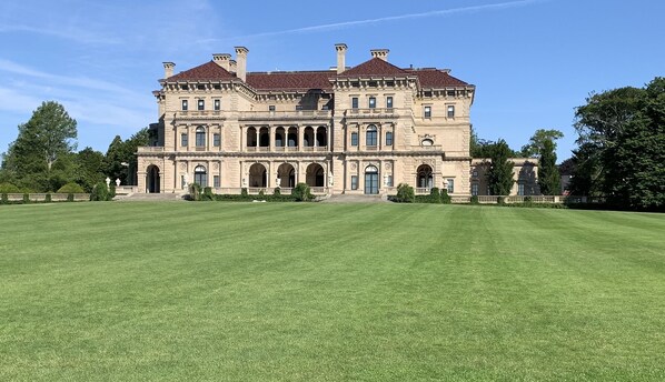 A large, historic building with a symmetrical facade, multiple arches, and a spacious lawn in front. - Beautiful home/neighborhood, near mansions, beach, Cliff Walk, town, 30 day min (Newport)